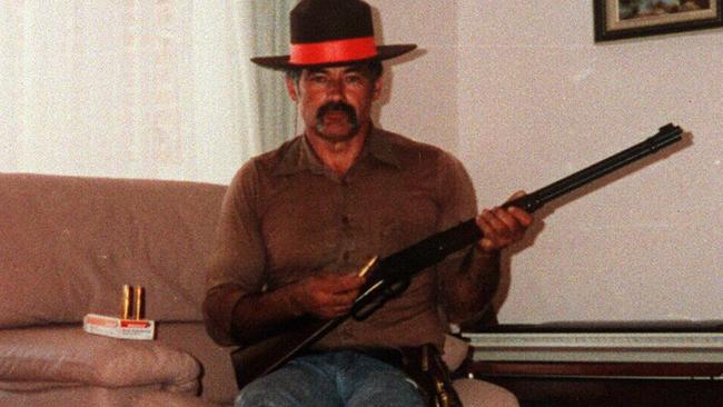 Ivan Milat, who was convicted of the murders of seven backpackers, wearing a sheriff's badge, poses in his lounge room with firearms.