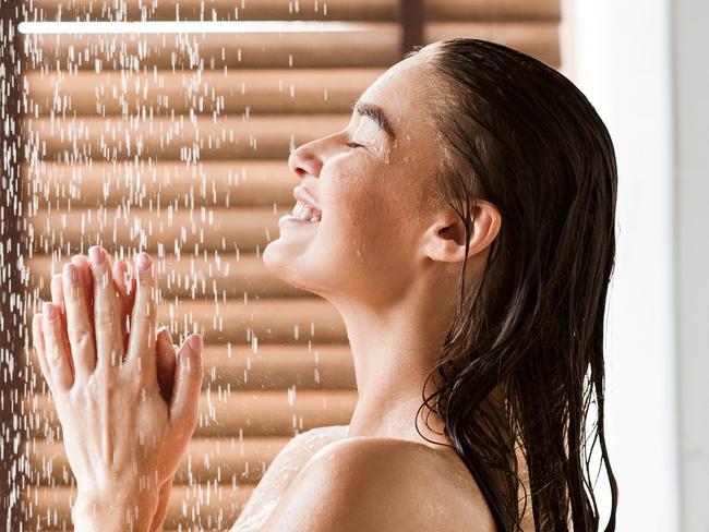 Woman Taking Shower Enjoying Water Splashing On Her, Side View  Picture: istock