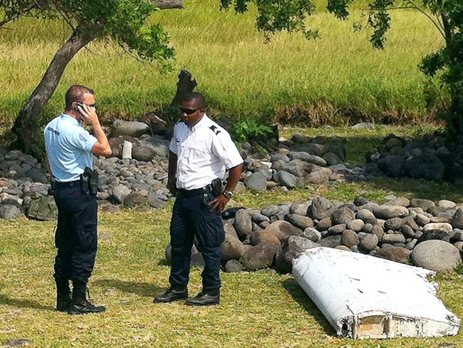 A policeman and a gendarme standing next to a piece of debris later identified from missing Malaysia Airlines plane MH370, found on the French Indian Ocean island of La Reunion. Picture: AFP