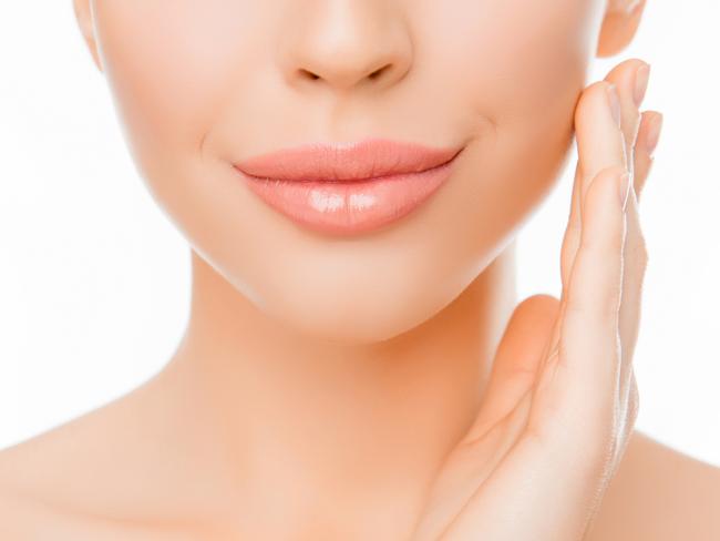 REAL DOLLS FEATURE stock image.Picture: iStock Close up of woman with perfect skin applying cream on face