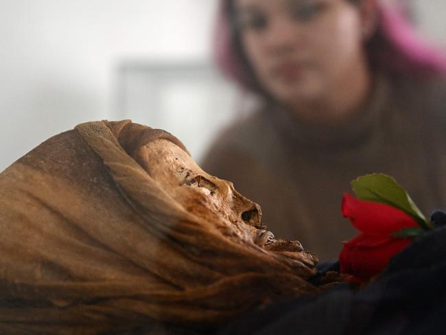 Daniela Betancourt, researcher of the National University, observes a mummy in the Jose Arquimedes Castro mausoleum museum, located at the cemetery in San Bernardo municipality, Cundinamarca department, Colombia on April 10, 2024. Clovisnerys Bejarano kneels to pray in front of the body of his mother, Saturnina, who died almost 30 years ago but whose facial features are preserved thanks to a mysterious mummification process that happens "spontaneously" in the Colombian town of San Bernardo. "For us as Sanbernardinos (mummification) has become our daily bread", explains Rocio Vergara, the person in charge of the exhibit where the bodies of Saturnina and 13 other people who also escaped decomposition for reasons not yet explained are on display. Some of them still have their eyes and fingernails. (Photo by Raul ARBOLEDA / AFP)