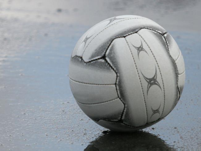 A Netball ball sitting on the court during the half-time break on a rainy day.