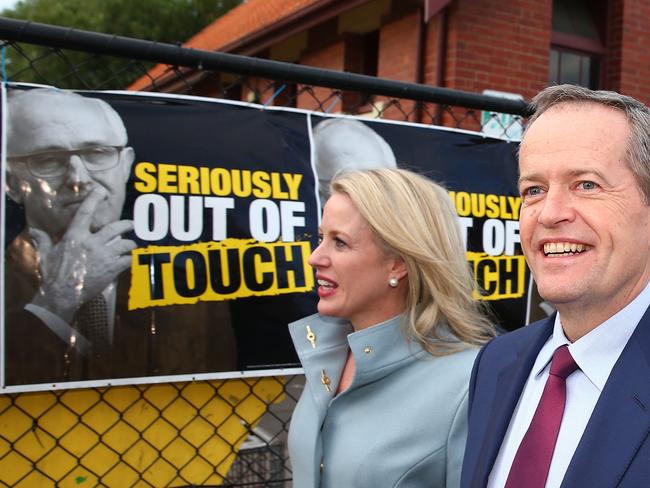 Bill Shorten, leader of the Opposition, and his wife Chloe Bryce walk past Malcolm Turnbull election posters after voting at Moonee Ponds West Primary School on July 2. Picture: Scott Barbour/Getty Images