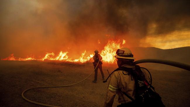 Firefighters spray water as they monitor flames caused by the Hughes Fire along a roadside in Castaic, Calif., Wednesday, Jan. 22, 2025. Picture: AP Photo/Ethan Swope