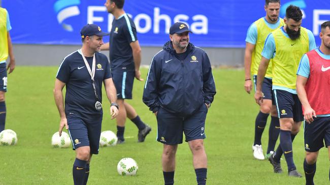 Australia head coach, Ange Postecoglou, center, walks on the field surrounded by his players.