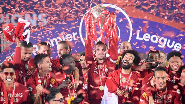 (FILES) In this file photo taken on July 22, 2020 Liverpool's English midfielder Jordan Henderson (C) raises the Premier League trophy during the presentation following the English Premier League football match between Liverpool and Chelsea at Anfield in Liverpool, north west England on July 22, 2020. – Liverpool and Manchester City remain the sides to beat after three seasons of unprecedented dominance but a rejuvenated Manchester United and free-spending Chelsea could force themselves into a four-way race for the title. (Photo by Laurence Griffiths / POOL / AFP)