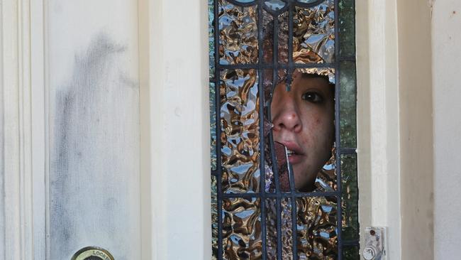 A woman peeks out of a smashed window at Sandery’s former home.