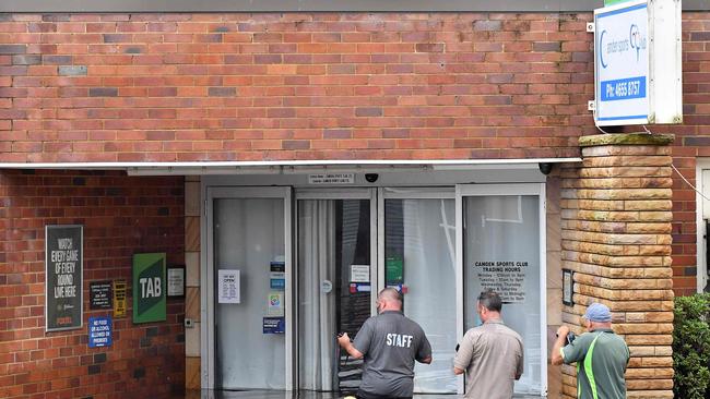 Camden Sports Club staff wade through the floodwaters to enter into the building. Picture: Muhammad Farooq/AFP