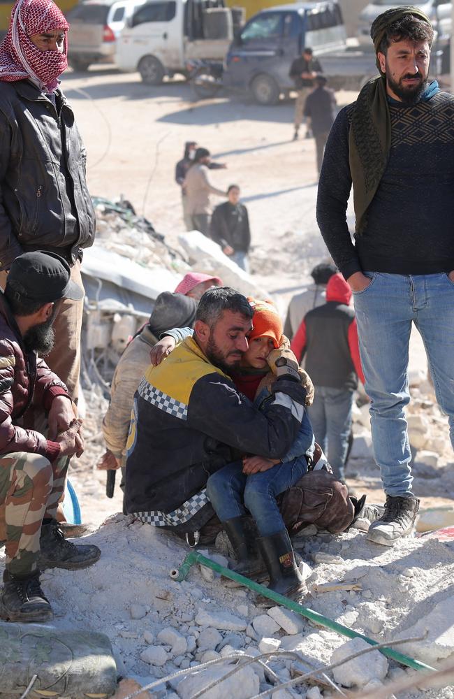 A Syrian White Helmet rescuer comforts a child amid the rubble of a building in the town of Harim in Syria's rebel-held northwestern Idlib province Picture: AFP