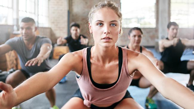 Shot of a group of people doing squats in a gym