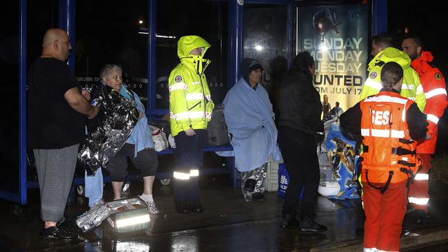 At a bus stop on Sackville Road, Canley Vale, ambulance officers and SES Crew help residents of Freeman Avenue who had to evacuate their homes as flood waters began to rise. Picture: John Appleyard