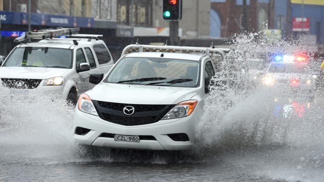 Vehicles drive through a partially flooded Paramatta Road in Leichhardt on Sunday. Picture: AAP