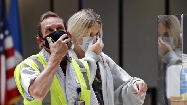 A worker and traveller adjust their protective masks at a security screening area at Seattle-Tacoma International Airport in Washington. Picture: Elaine Thompson/AP