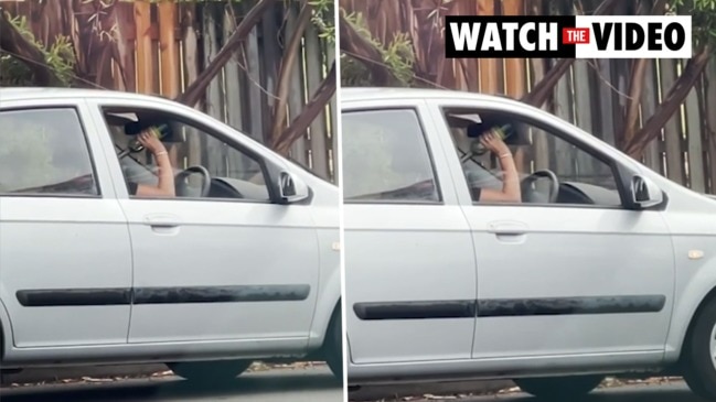 Woman drains wine bottle at wheel of car 