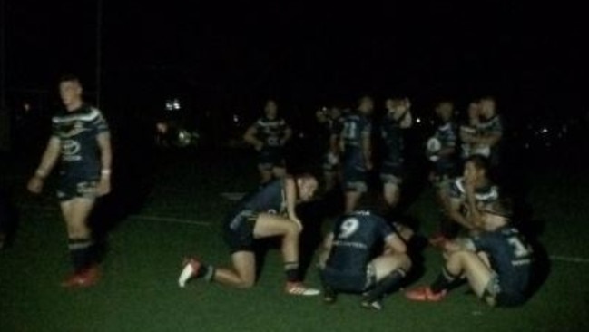 Cowboys players sit on the field in the dark after a blackout hit Cairns prior to kick-off.