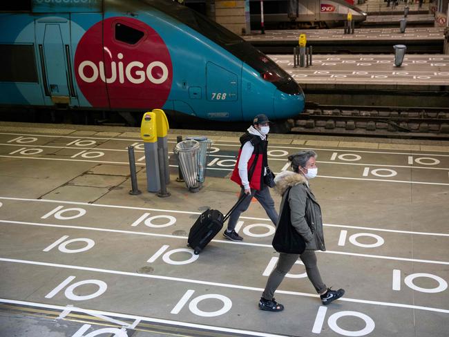 Travellers wearing protective mask walk next to a train past social distancing marks on the ground at the Gare Montparnasse train station in Paris. Picture: AFP