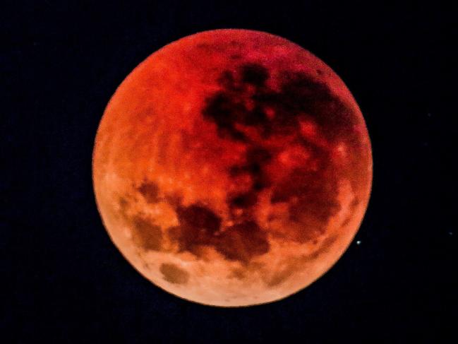 A total lunar eclipse is pictured as seen from underneath Sydney's Harbour Bridge. As the eclipse reaches its peak, refracted light from the sun caused the moon to appear red, otherwise known as the 