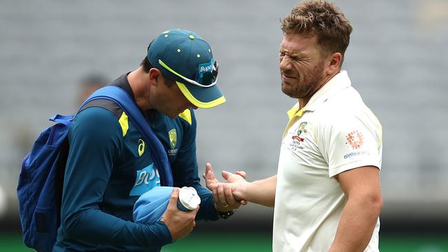 Aaron Finch seen to by Australian Team Physiotherapist David Beakley after he was struck on the hand. Picture: Getty Images