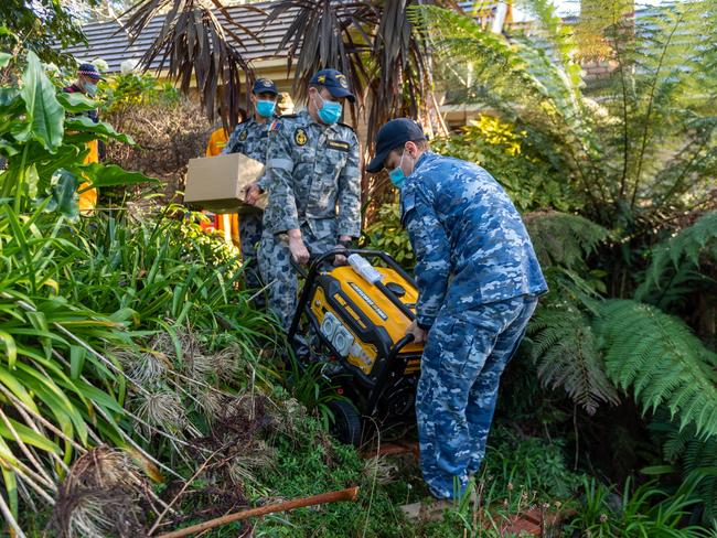 Members of the Australian Defence Force work together to deliver a generator to a storm-affected resident in Olinda in Victoria, which has been without power for over a week.