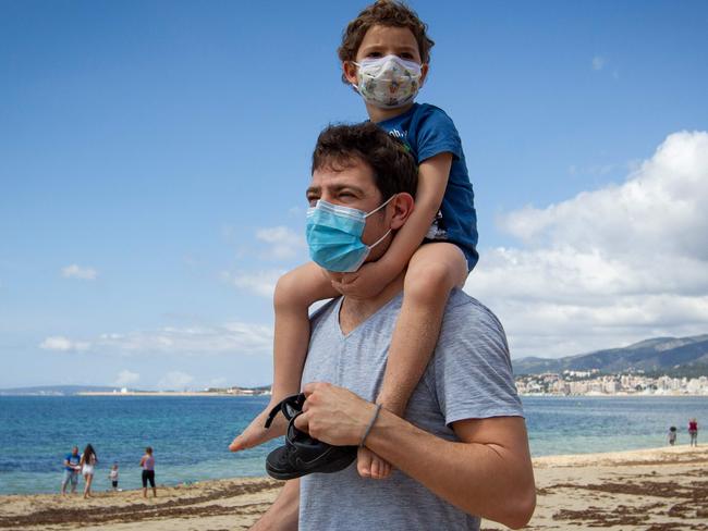 A father carries his son on his shoulders at Can Pere Antoni Beach in Palma de Mallorca, Spain, which is looking to ease lockdowns. Picture: AFP