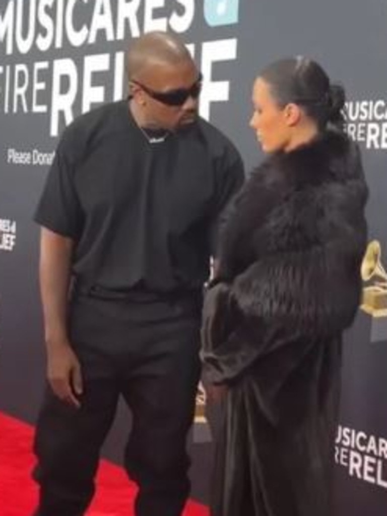 Kanye West can be seen telling Bianca Censori to drop her coat on the Grammys red carpet. Picture: CBS