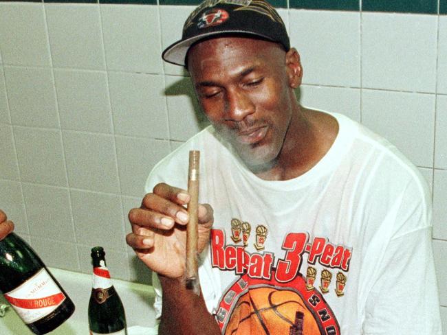 Michael Jordan of the Chicago Bulls enjoys a cigar in the locker room 14 June after winning game six of the NBA Finals against the Utah Jazz at the Delta Center in Salt Lake City, UT. The Bulls won the game 87-86 to win their sixth NBA Championship.  AFP PHOTO/MIKE NELSON (Photo by MIKE NELSON / AFP)