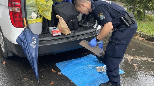 NSW Police inspect a firearm from a burnt-out car in Berala. Picture: Liam Mendes / The Australian