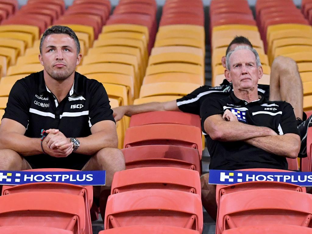 Sam Burgess (left) and Rabbitohs coach Wayne Bennett (right) are seen sitting in the empty grandstands during the round two NRL match between the Brisbane Broncos and South Sydney Rabbitohs at Suncorp Stadium in Brisbane, Friday, March 20, 2020. (AAP Image/Darren England) NO ARCHIVING, EDITORIAL USE ONLY