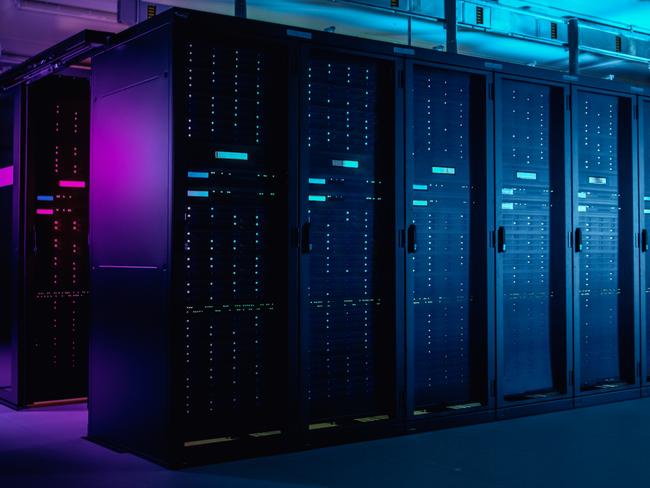 In Data Center: IT Technician Running Maintenance Programme on Laptop, Controls Operational Server Rack Optimal Functioning. Modern High-Tech Telecommunications Operational Data Center in Neon Lights.