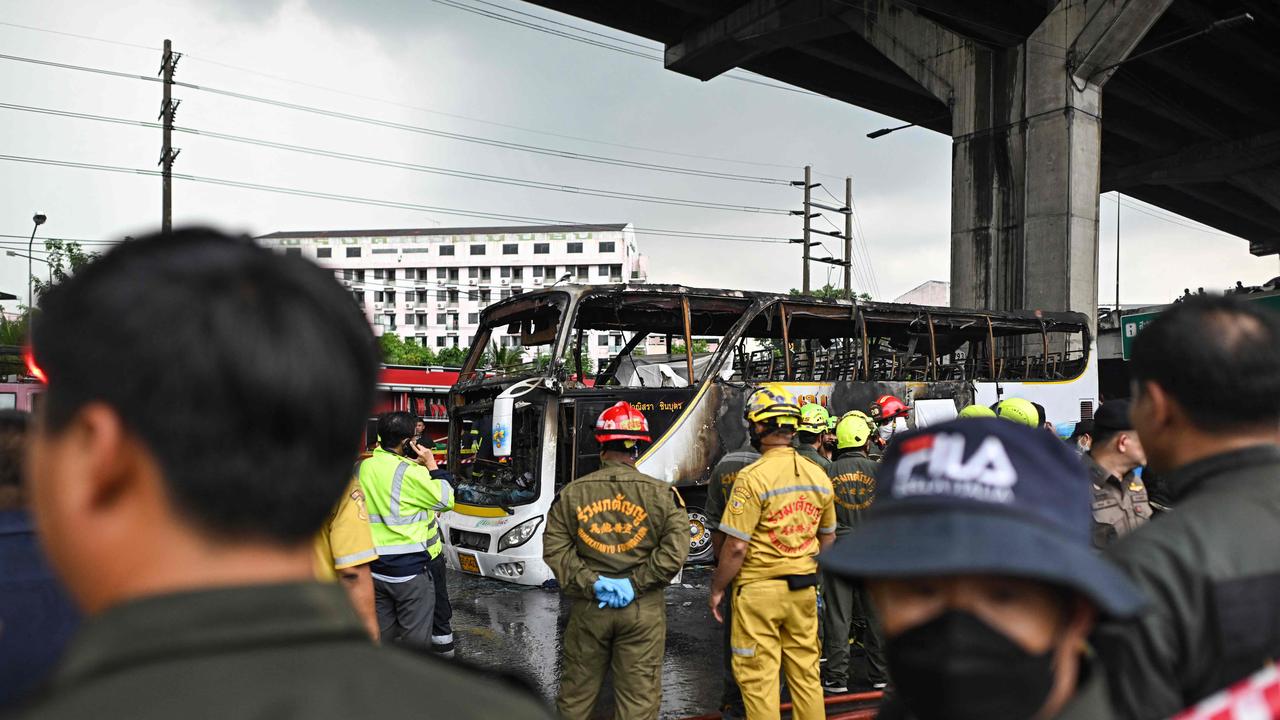 Firefighters and rescue workers stand next to a burnt-out bus that was carrying students and teachers on the outskirts of Bangkok, on October 1, 2024. (Photo by Manan VATSYAYANA / AFP)