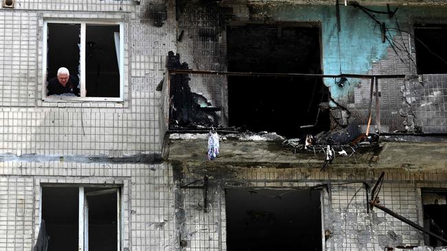A local resident looks out of the window of his flat in a multistorey residential building, damaged following a Russian drone strike on Kyiv on May 24, 2025, amid Russian invasion in Ukraine. Picture: Sergei Supinsky / AFP.