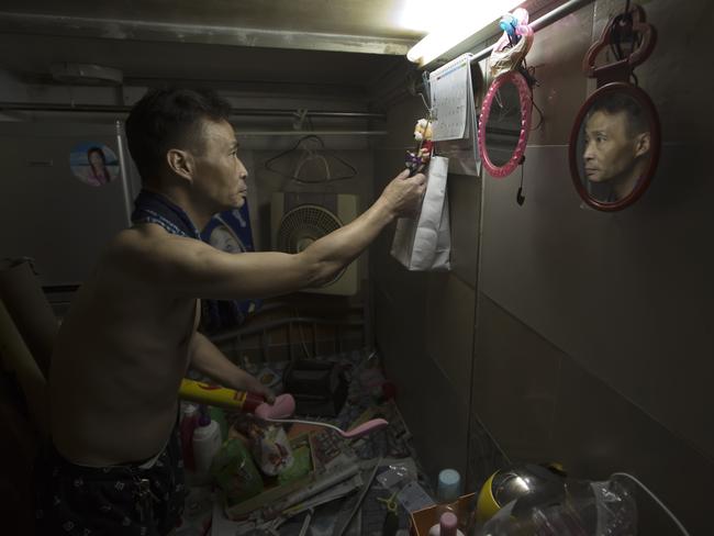 Sin, 55, tidies up the bed in his home. Picture: Kin Cheung/AP