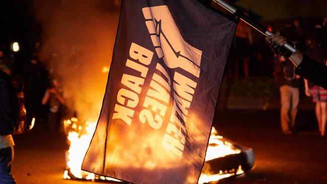 A Black Lives Matter flag waves in front of a fire at a police station. Picture: Allison Dinner/AFP