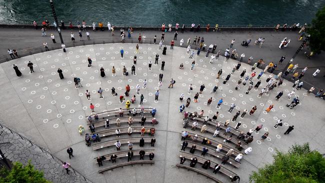 Outside is safer — with restrictions such as these people wearing face masks and sitting and standing as they follow the social distancing measures in Lourdes, southwestern France. Picture: Laurent Dard/AFP