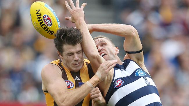 Joel Selwood handballs over his head as he’s bumped by Isaac Smith. Picture: Michael Klein