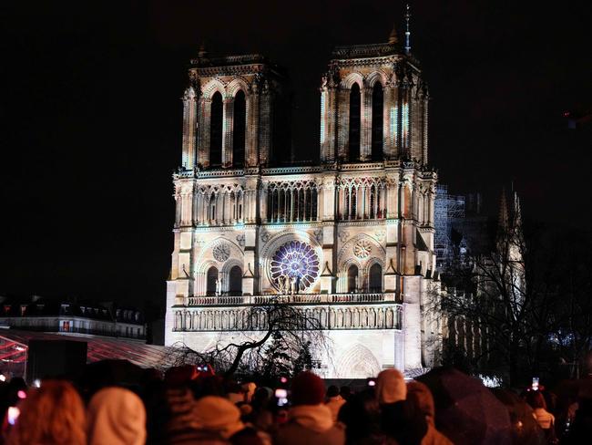 Crowds stand outside Notre-Dame Cathedral as it is illuminated during a ceremony to mark its re-opening. Picture: AFP