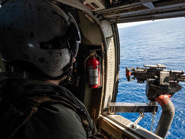 A flight crew member looks out from a helicopter launched from the USS Carl Vinson aircraft carrier on a flight to visit the Japan Maritime Self-Defense Force's Hyuga-class helicopter destroyer "JS Ise", during a three-day maritime exercise between the US and Japan in the Philippine Sea, between Okinawa and Taiwan, on January 31, 2024. (Photo by Richard A. Brooks / AFP)