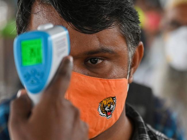 A health worker checks the body temperature of a passenger during a Covid-19 screening as he arrives at a railway platform on a long distance train, in Mumbai. Picture: AFP