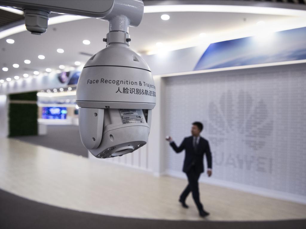 A Huawei reception employee walks by a display for facial recognition cameras. Picture: Getty