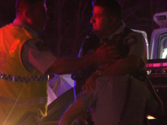 A distressed officer is comforted by colleague at the scene. Picture: TNV