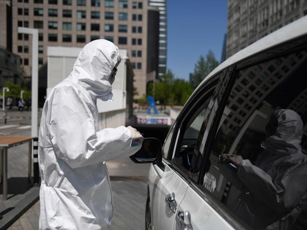 A worker collects information from a driver at the entrance to the car park of a commercial complex in Beijing. Picture: AFP