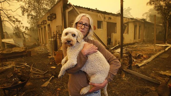 Jann Gilbert with her dog, Ollie, visits the site of her burnt-out unit in Mallacoota. Picture: David Caird