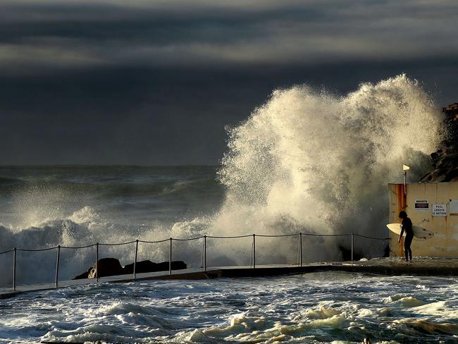 A surfer carefully waits at the Bronte pool to tackle the big surf in Sydney at dawn this morning. Picture. Phil Hillyard