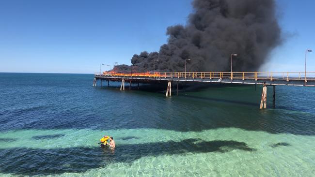 An off-duty police officer rescuing an injured welder after the jetty caught on fire. Picture: SAPOL