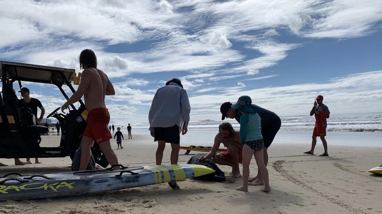 Surf Life Saving Queensland lifeguards tend to a woman and boy who were pulled from rough surf at Alexandra Headland on Sunday morning. Picture: Stuart Cumming