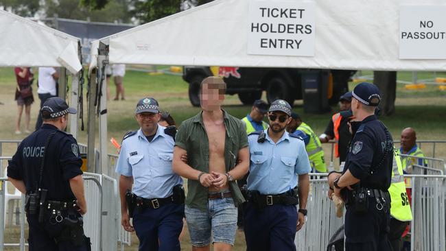 Police escort this man from the Electric Gardens festival at Centennial Park. Picture: Matrix 