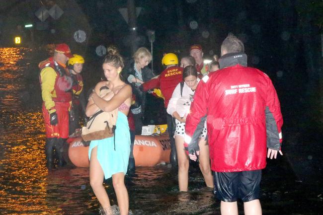 Narrabeen locals are evacuated by Surf Rescue from their homes as flood waters rise. Picture: Damian Shaw