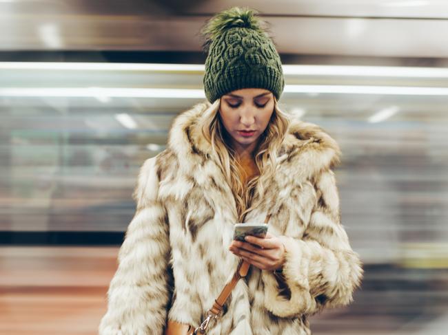 Depressed young girl uisng her phone while waiting for her traing on the subway