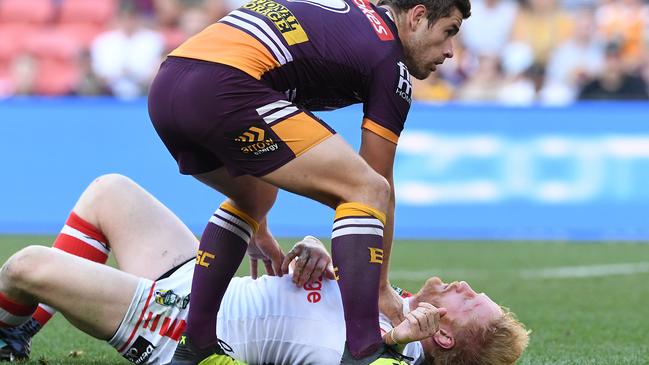 Andrew McCullough of the Broncos assists James Graham of the Dragons as he lies concussed on the field during a 2018 elimination final.