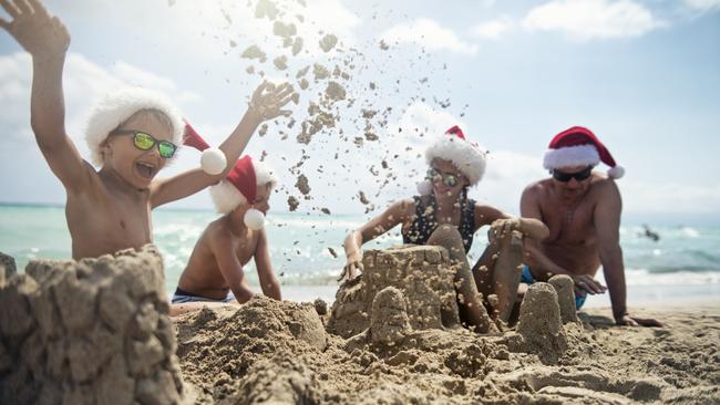 SHFG summer. It's summer Christmas on the beach. Kids and grandfather wearing Santa hats are building sandcastles on the beach. Picture: iStock